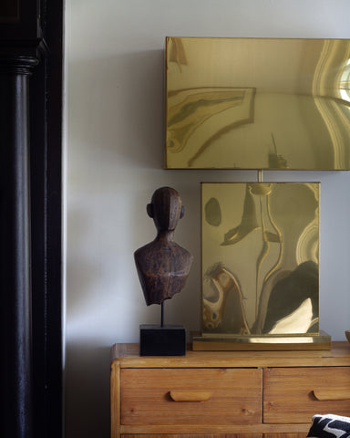 Wooden dresser with decorative items including a bronze bust and gold table lamp. These vintage items were curated by Parliament Interiors in Vancouver, BC. 